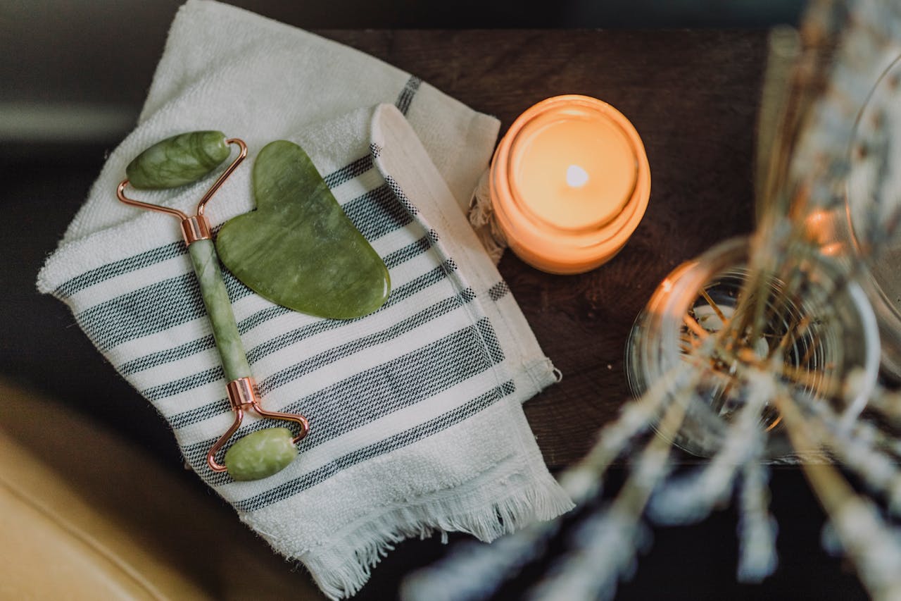 Services A serene spa setup featuring a jade roller, gua sha, towel, and candle for ultimate relaxation.